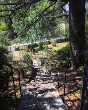 Un escalier en pierre mène à travers un jardin, avec des rampes de chaque côté.