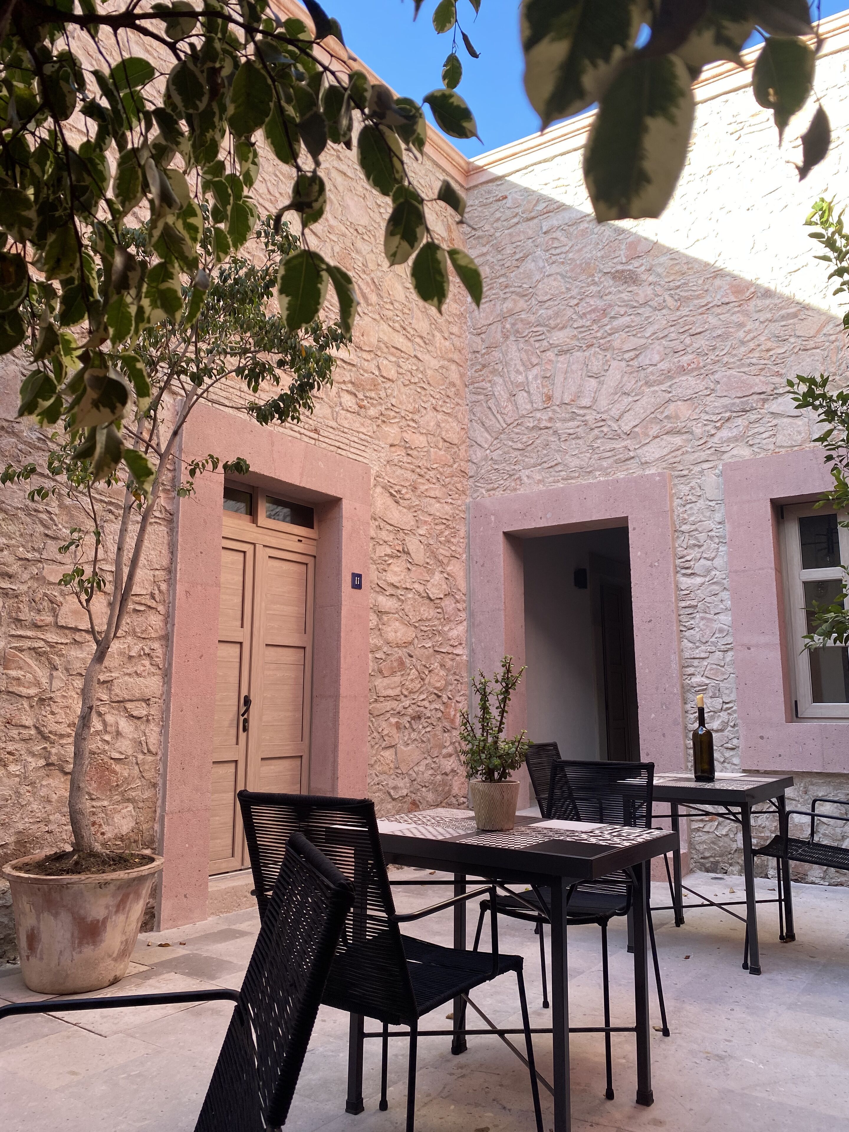 An outdoor seating area with stone walls, a wooden door, and a potted plant.