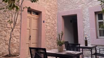 An outdoor seating area with stone walls, a wooden door, and a potted plant.