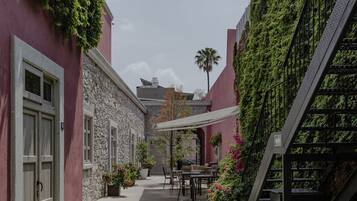 Un patio con escalera, zona de estar y un pequeño jardín.