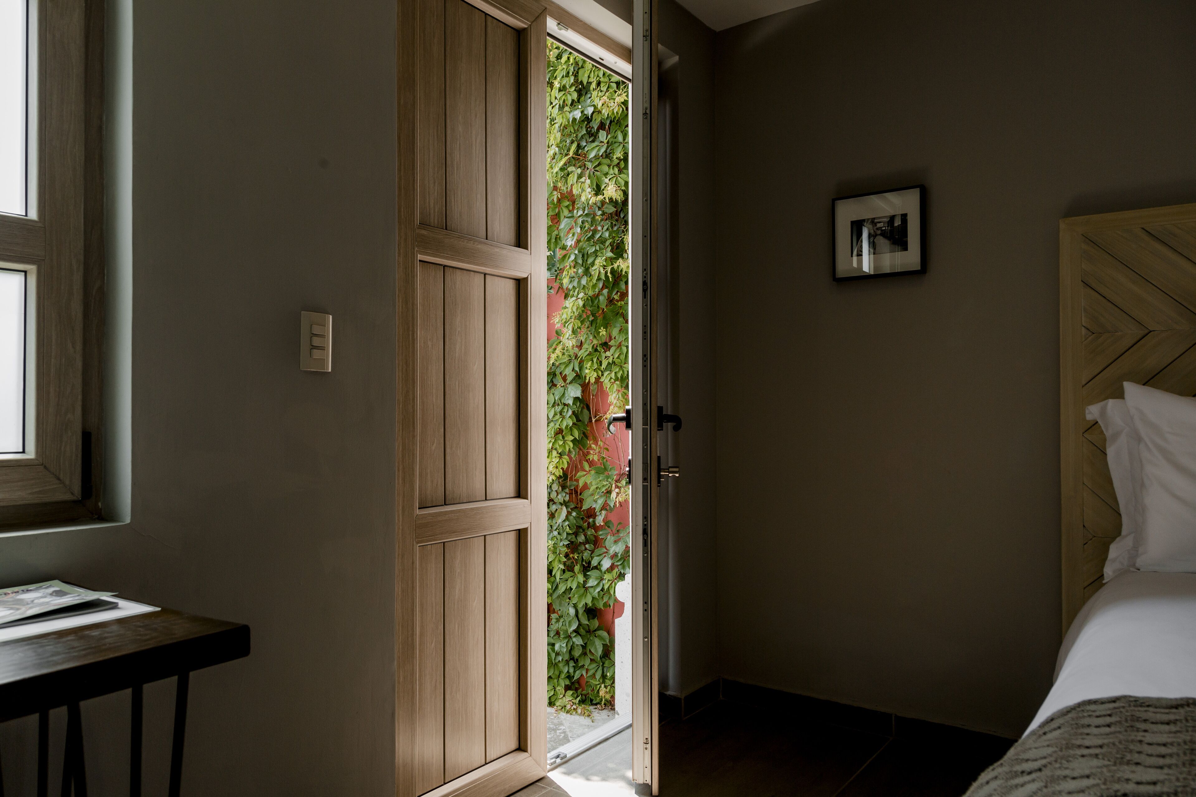 Une chambre à coucher avec un lit, une porte en bois, une petite table et une fenêtre.