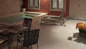 Zona de piscina al aire libre con mesa y sillas, un jacuzzi y una puerta con el número 14.
