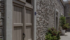 Un edificio de piedra con una puerta doble de madera y una planta en maceta a su lado.