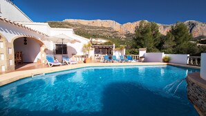 Une piscine avec des chaises longues et une vue sur les montagnes.