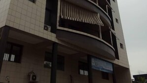 A multi-story building with a tiled facade, balconies, and a sign indicating a business or service on the ground floor. - PRETTY T3 EQUIPPED COCODY (Cocody)