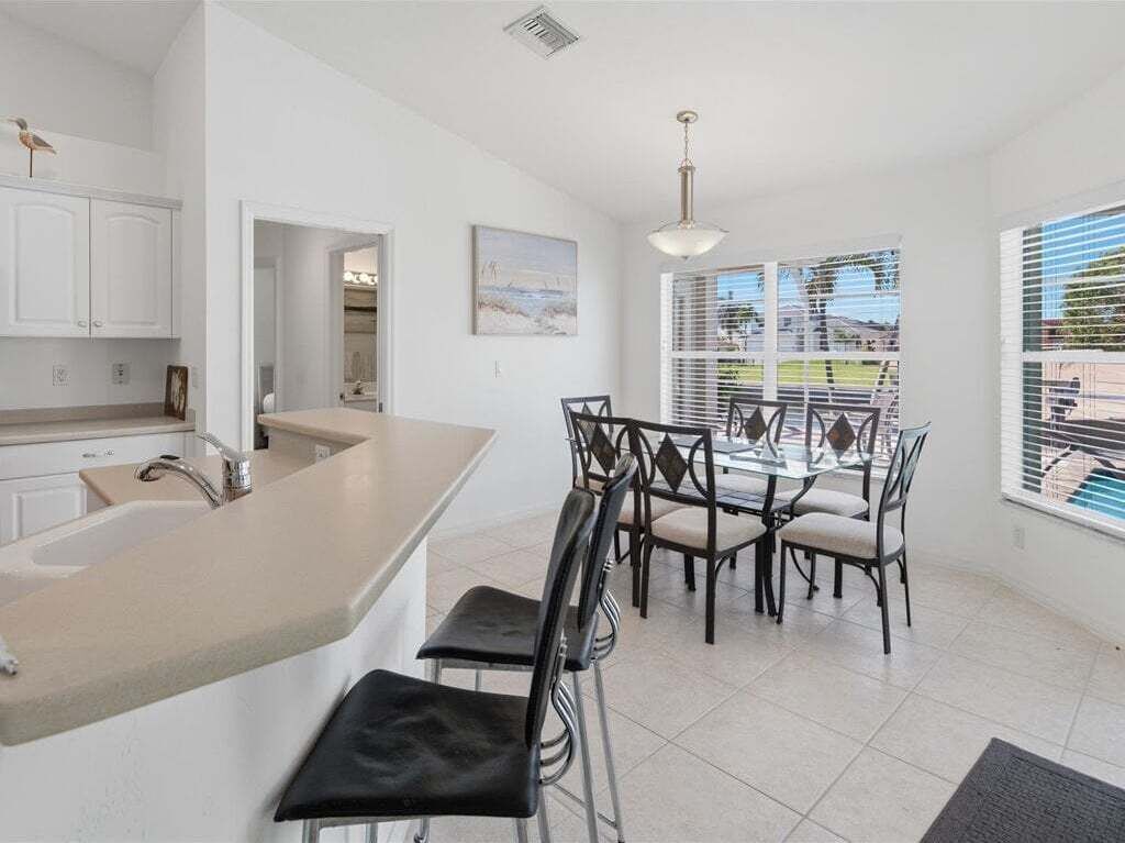 A modern kitchen with a large island, bar stools, and a dining area with a table and chairs.