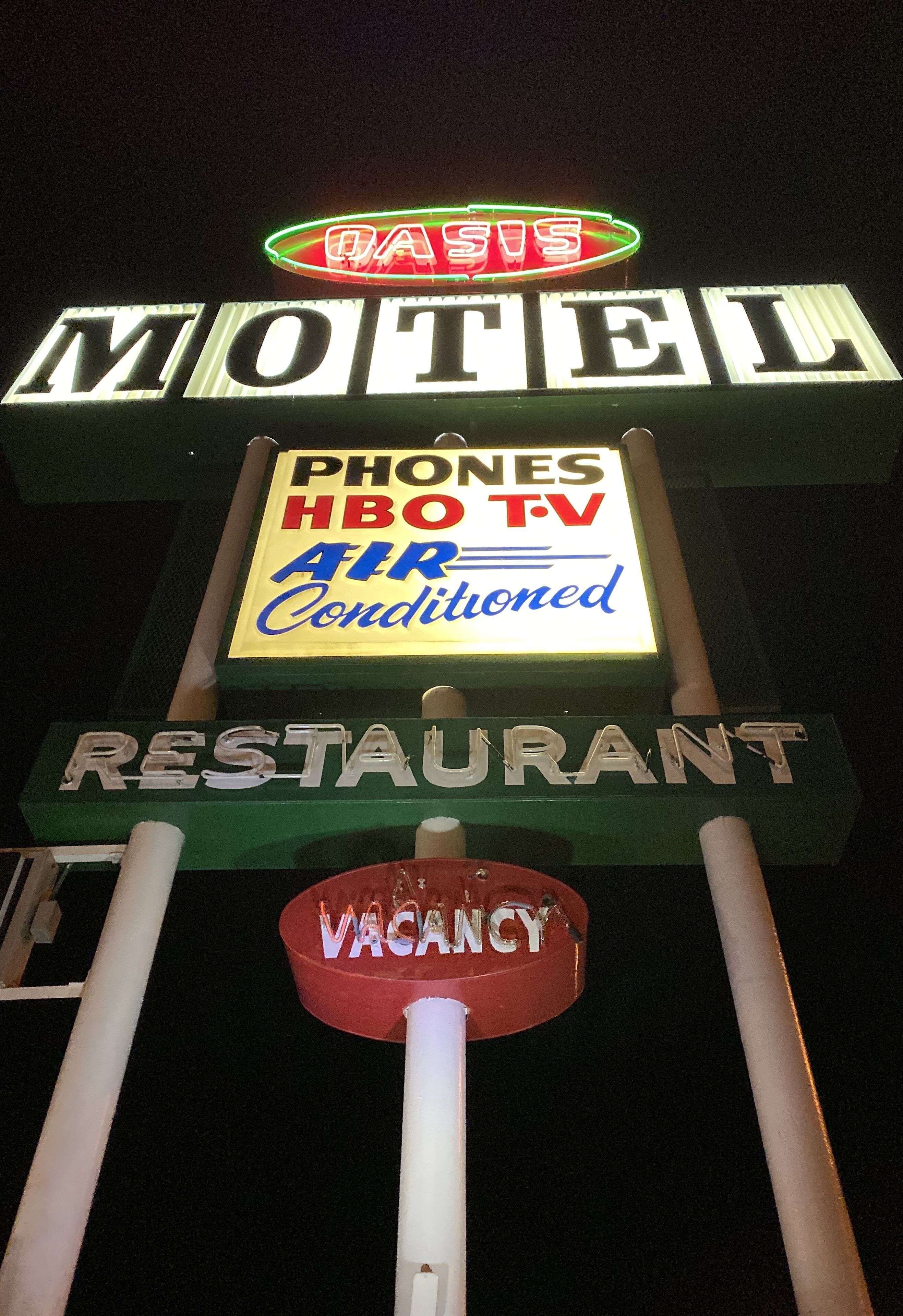A motel sign with amenities including phones, HBO TV, and air conditioning.
