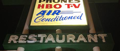 A motel sign with amenities including phones, HBO TV, and air conditioning.