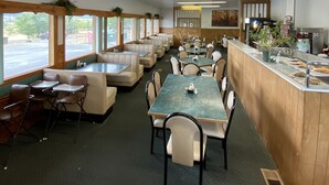 A restaurant with booths, tables, and a counter with a beverage station. - Oasis Botique Motel (Raton)
