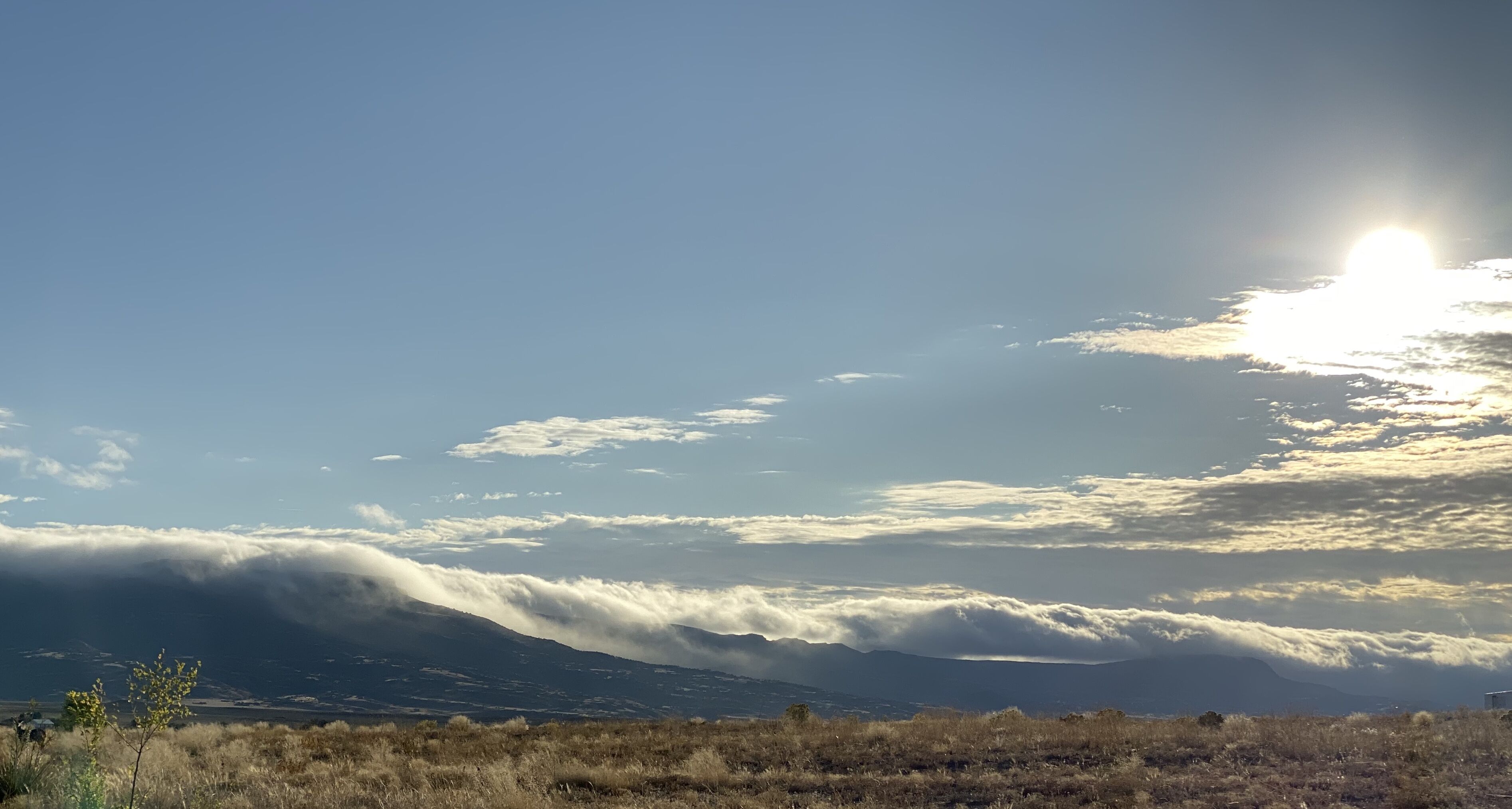 Paisaje de montaña con nubes y el sol.