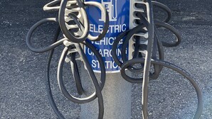 A car charging station with a sign indicating it's for car charging only, located in front of a building with a sign for Oasis Hotel - Restaurant. - Oasis Botique Motel (Raton)