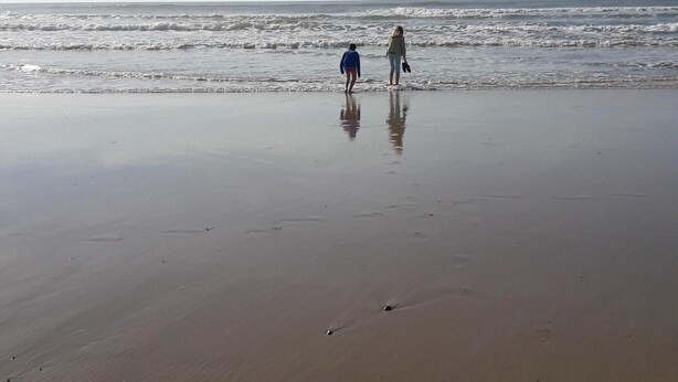 Una spiaggia con due persone che camminano verso l'acqua.