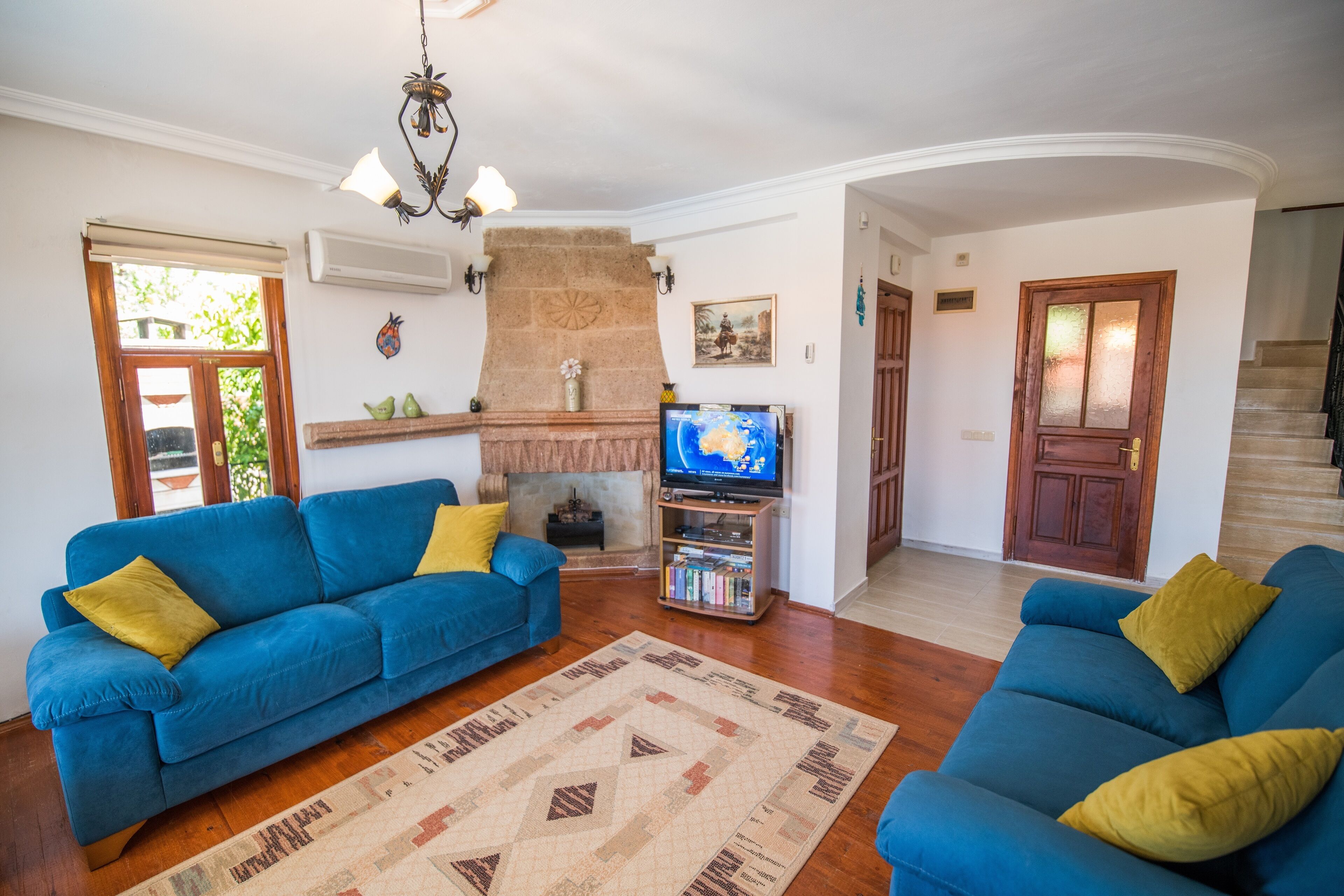 A living room with two blue sofas, a fireplace, a television, and a bookshelf.