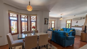 A spacious living area with a glass dining table, blue sofa, and wooden flooring. - Spacious Villa with WiFi, A/C,  Private Pool and Rooftop Terrace
Licence 07-540  (Kalkan)