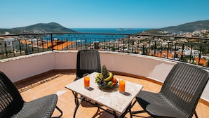 A balcony with a table, two chairs, a fruit bowl, and two glasses of orange juice. - Spacious Villa with WiFi, A/C,  Private Pool and Rooftop Terrace
Licence 07-540  (Kalkan)