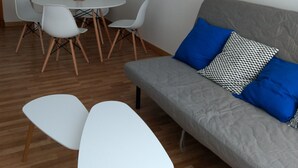A modern living room with a grey sofa, white chairs, and a round dining table. - In the historic center of Ourense, it is ideal for families or groups  (Ourense)