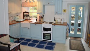 Une cuisine avec des meubles de couleur bleu clair, un plan de travail en bois, un four encastré et une fenêtre donnant sur l’extérieur.