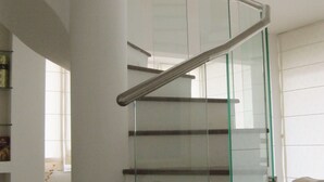 Un interior moderno con una escalera de cristal, un sofá y una mesa de centro.