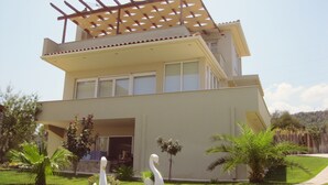Una casa moderna de dos pisos con techo plano, balcón y pérgola.