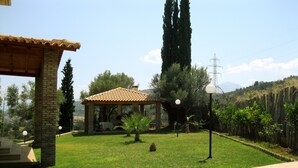 Un espacio al aire libre techado, con techo de baldosas, pared de piedra y un camino pavimentado.