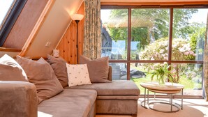 A cozy room with a sectional sofa, a small round table, and a large window offering a view of the outdoors. - Loch view location in Holiday park, sleeps 4 persons, off road parking, free Wi-Fi (Dunoon)