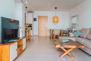 Un salon moderne avec un téléviseur, une table basse en bois et un canapé. On y trouve également un coin repas avec des chaises et une table.
