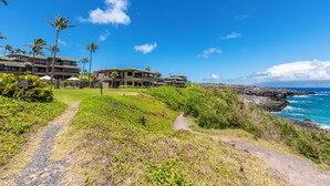 Un hôtel situé sur la côte, composé de plusieurs bâtiments, avec un sentier menant à la plage et offrant une vue sur l’océan.
