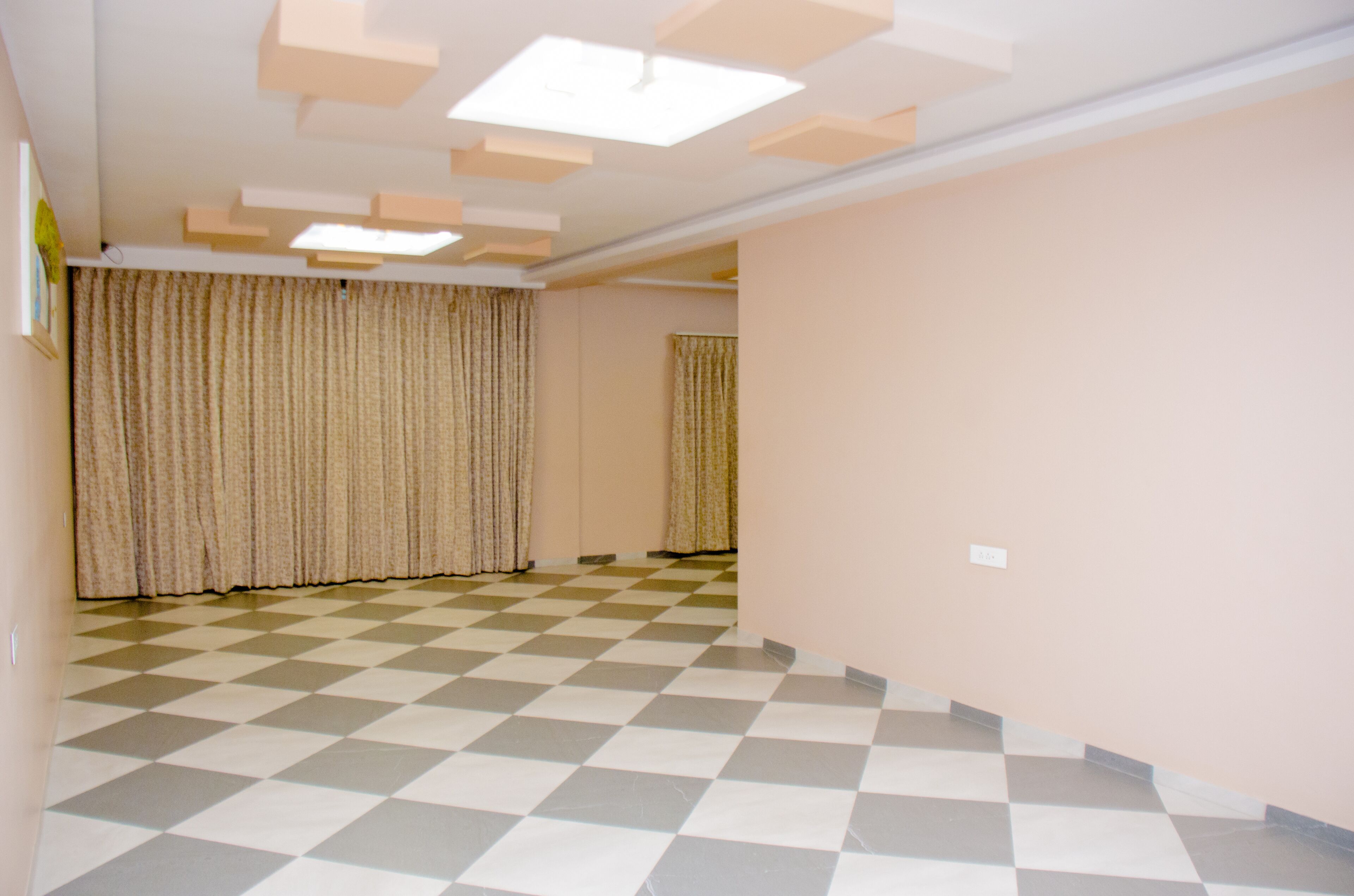 A room with a checkered floor, beige curtains, and a light-colored wall.