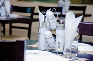 Una mesa de comedor preparada con servilletas blancas, una jarra de vidrio y un salero y pimentero.