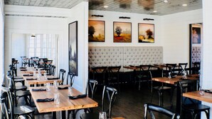 A restaurant with long wooden tables, black chairs, and artwork on the walls. - Dahlonega Resort and Vineyard (Dahlonega)