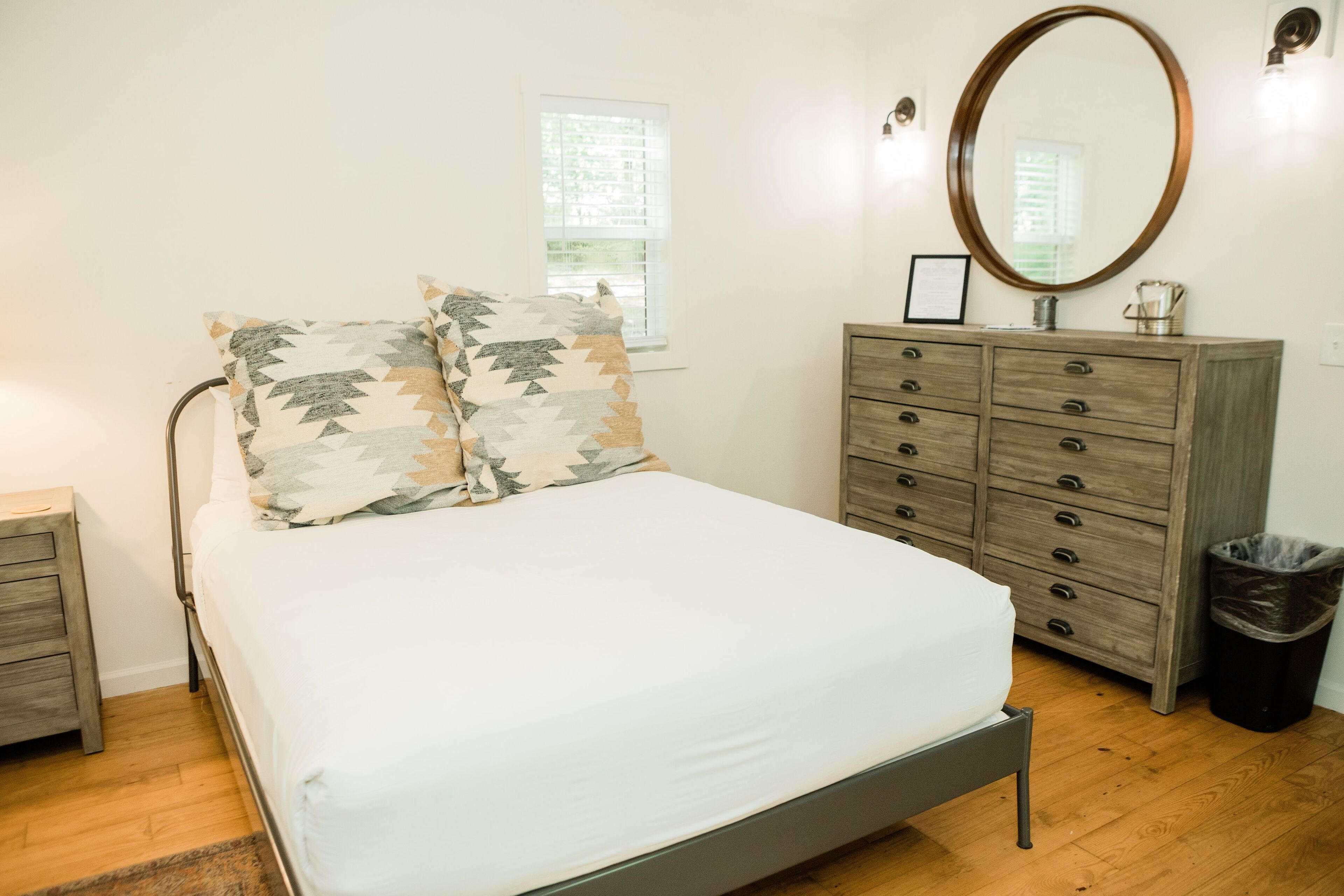 Une chambre à coucher avec un lit, une commode, un miroir et une fenêtre.