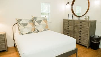 Une chambre à coucher avec un lit, une commode, un miroir et une fenêtre.