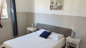 A neatly arranged bedroom with a large bed, two bedside tables, a chair, and a wall-mounted artwork.