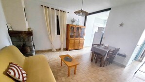 A living room with a sofa, a small table, a cabinet, and a dining area with chairs and a table.