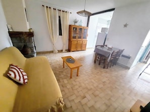 Un salon comprenant un canapé, une petite table, un meuble et un coin repas avec des chaises et une table.