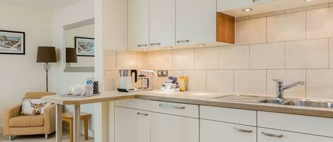 A modern kitchen with white cabinets, a stainless steel sink, and a wooden countertop.