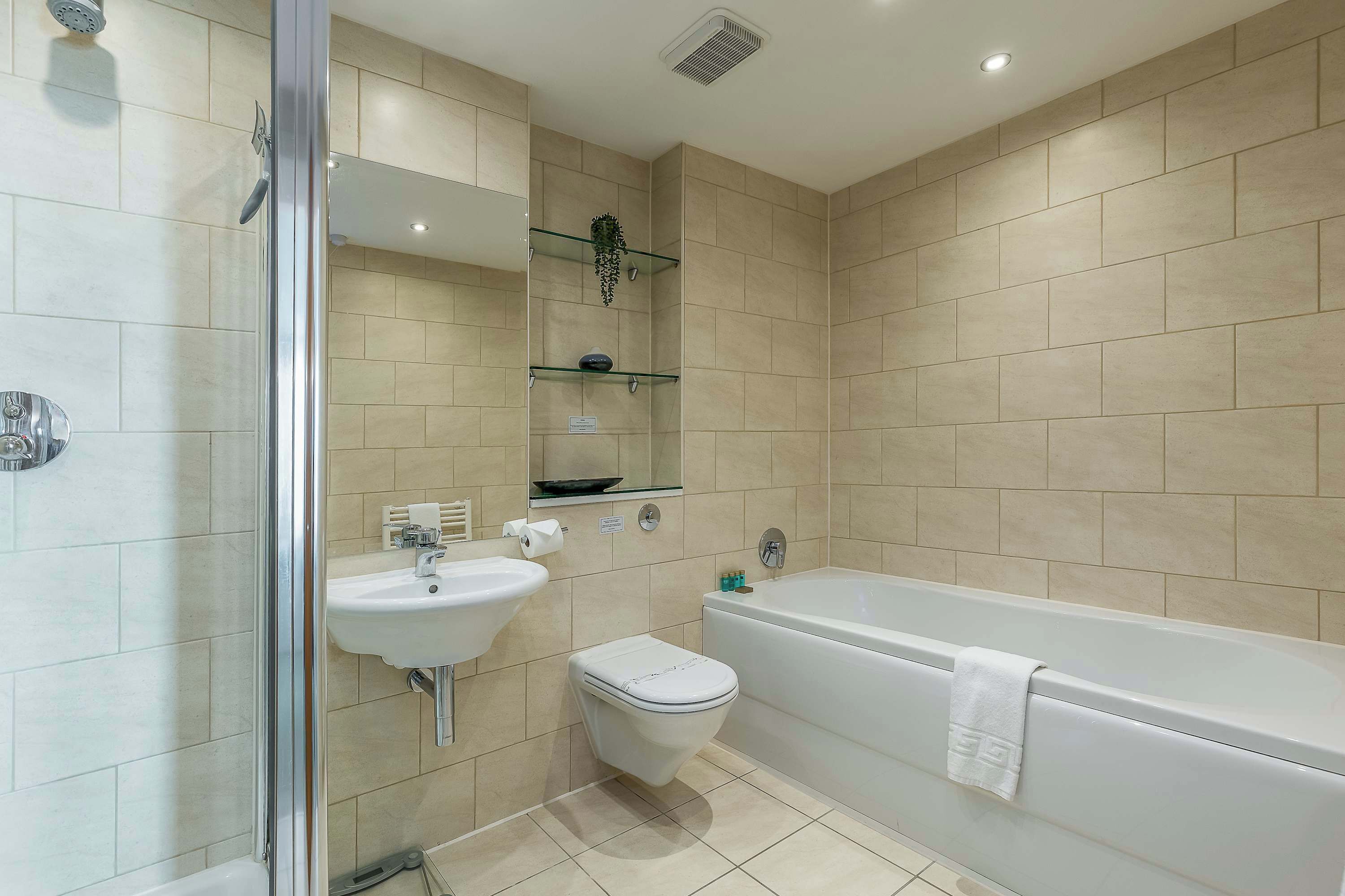 Ein modernes Badezimmer mit Duschkabine aus Glas, Waschbecken, Toilette und Badewanne.