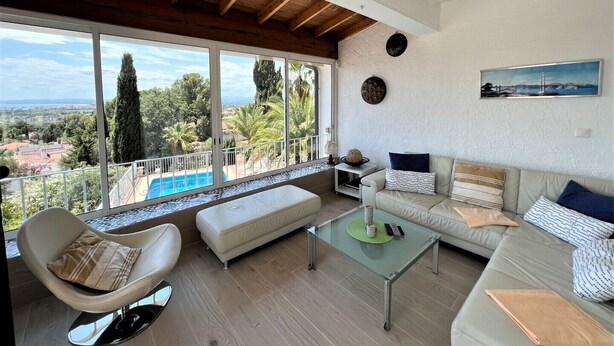 A spacious living room with a large window overlooking a pool and greenery. - Holiday house - privatpool + glass fiber, views + aircondition, Wallbox (3,7kW) (El Mas Fumats)