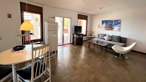 A modern living room with a dining area, a sofa, a TV, and a painting on the wall. - Holiday house - privatpool + glass fiber, views + aircondition, Wallbox (3,7kW) (El Mas Fumats)