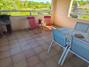 Ein Balkon mit Tisch, Stühlen, einem Grill und einem Blumentopf.