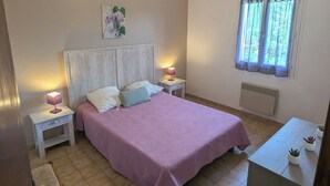 Een slaapkamer met een bed, nachtkastjes, een raam en een radiator.