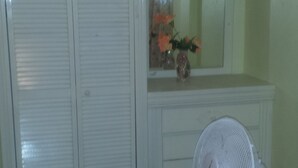 Un baño con un tocador blanco, un espejo, un ventilador y piso de baldosas.