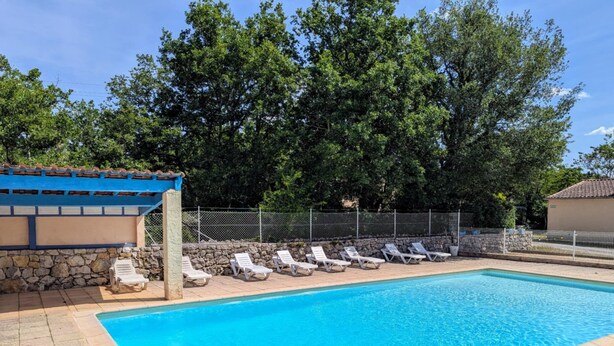 Piscina com espreguiçadeiras e parede de pedra.