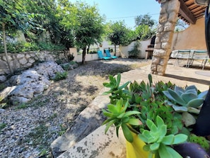 Ein Gartenbereich mit Steinmauer, kleinem Pool und Sitzgelegenheit im Freien.