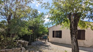 Um edifício rústico com entrada por um caminho de cascalho e árvores ao redor.