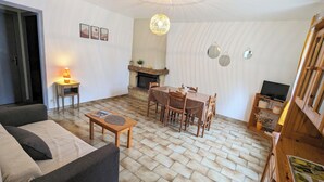 Uma sala de estar acolhedora com lareira, uma mesa de jantar e um sofá.
