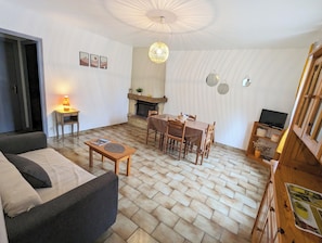 Ein gemütliches Wohnzimmer mit Kamin, Esstisch und einer Couch.