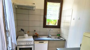 Uma cozinha compacta com fogão, forno, lava-louças, pia e uma janela acima da pia.