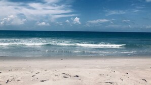 Une plage avec un ciel dégagé et une mer calme.