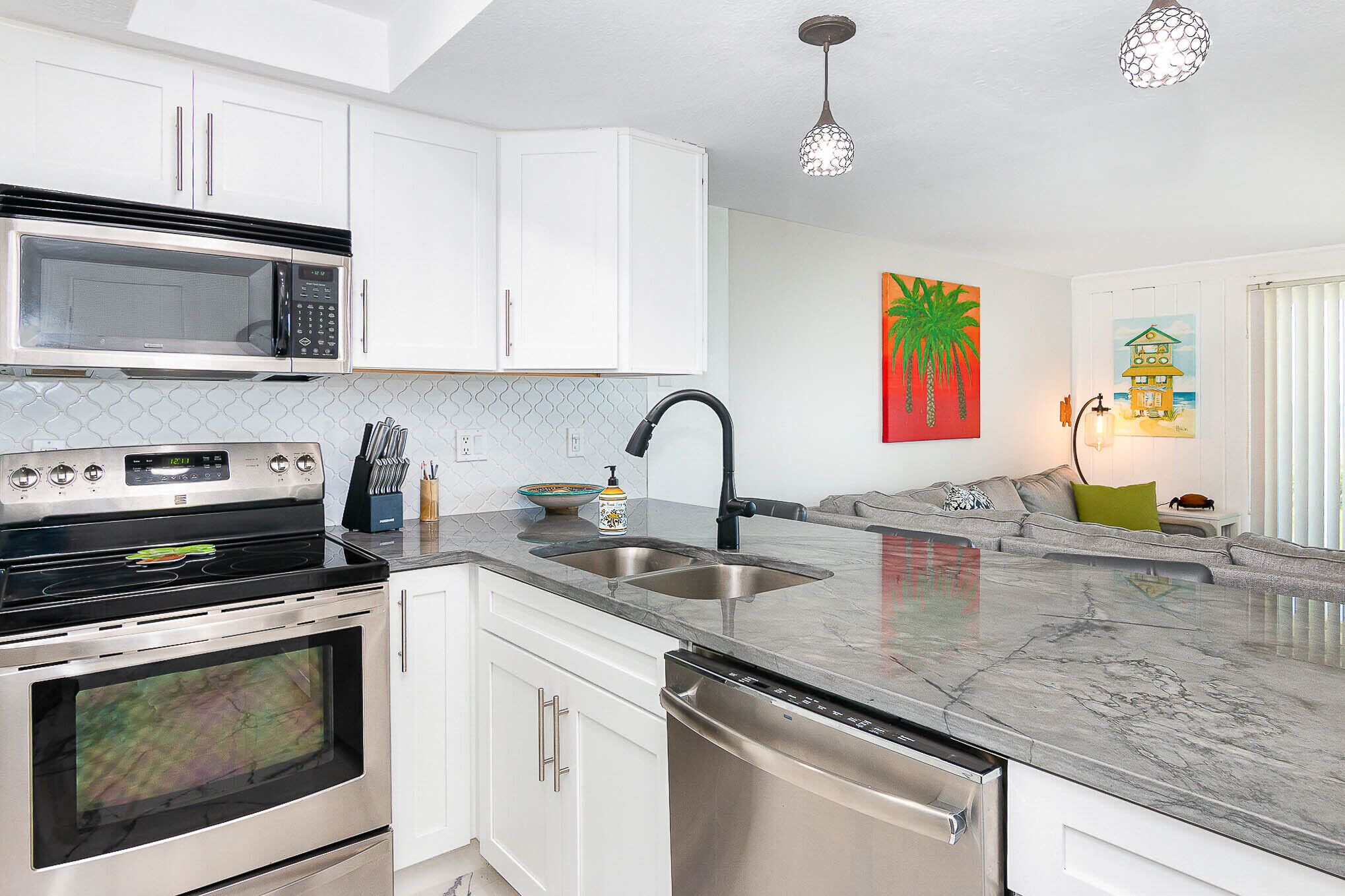 A modern kitchen with white cabinets, stainless steel appliances, and a marble countertop.